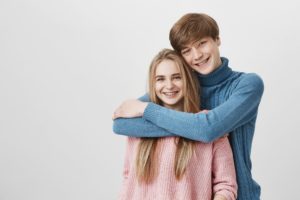 Teen couple with braces embracing
